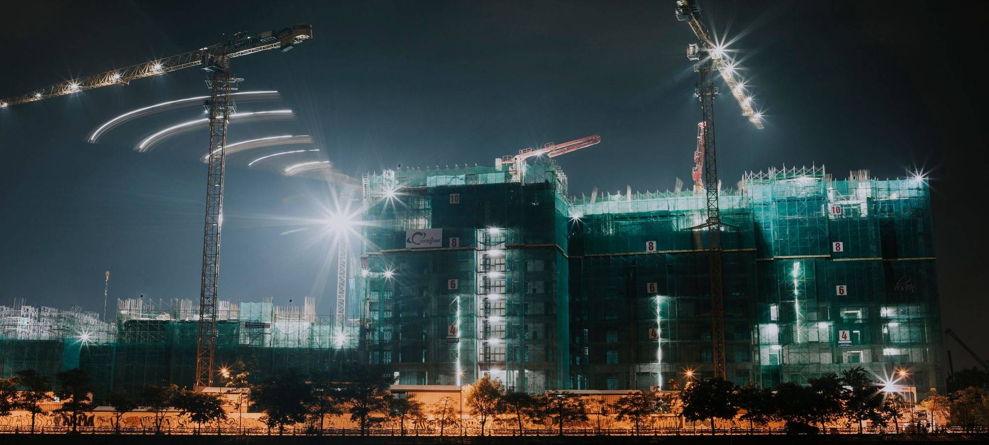 Baukräne über einer Großbaustelle in der Abenddämmerung