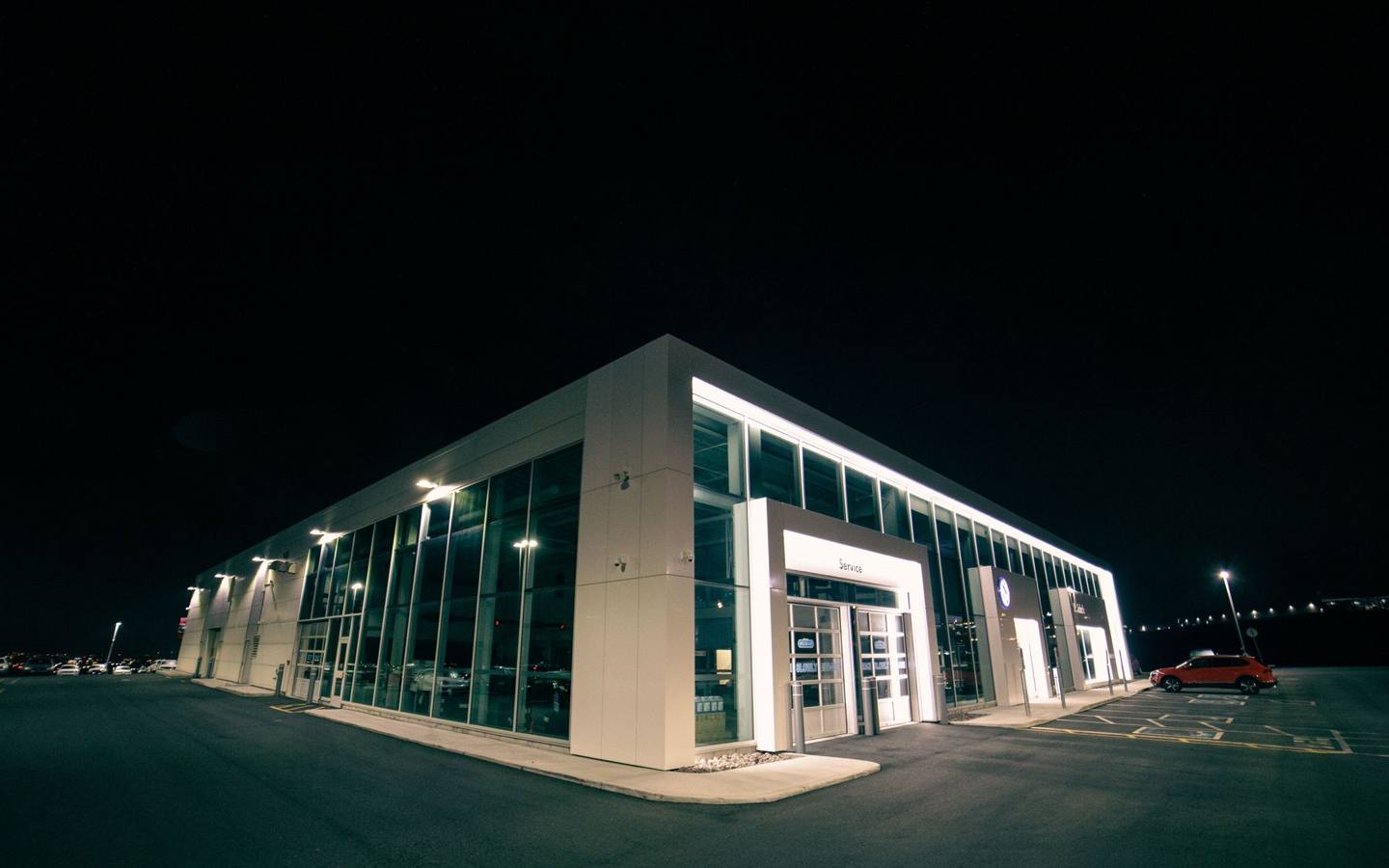 Beleuchtetes Gewerbeobjekt mit Fahrzeugen am Abend